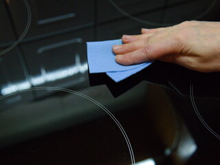 A woman's hand wipes the cooking panel