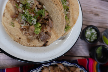 Top view of a table with a pair of carnitas tacos.
