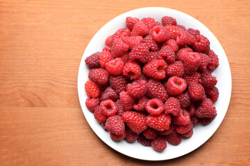 Ripe red raspberries on a white plate. Sweet raspberry background. Berries close-up. Healthy food....