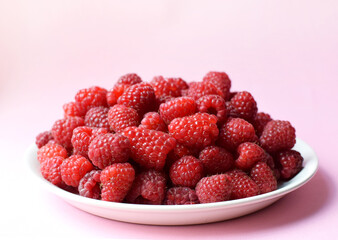 Ripe red raspberries on a white plate. Sweet raspberry background. Berries close-up. Healthy food