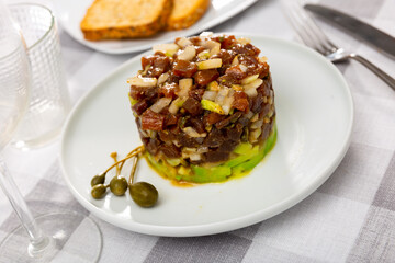 Appetizing tuna tartare with avocado and quinoa on plate in restaurant