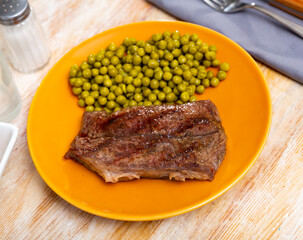 Homemade delicious dinner of grilled beef steak with pickled green peas served on plate ..