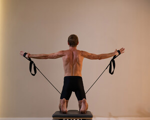 A man doing Pilates on a reformer. 