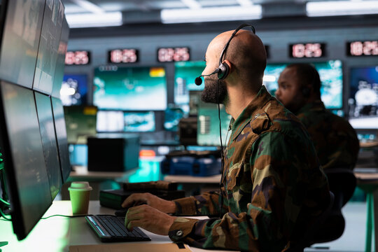 Military dispatcher in command post ready to respond to emergencies and communicate with soldiers on front lines. Middle Eastern war telecommunications operator in uniform talking in headset mic