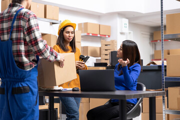 Asian employees team in small business fulfillment center managing boxes, attaching shipping labels...