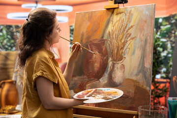 Female painter using watercolor paint and mixing colors on palette for her artistic creation in...
