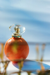 Orange perfume bottle on white background and sun rays