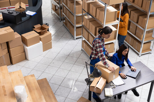 Local brand supply room staff work at distribution hub for order processing and hand packing merchandise. Ensuring local shipping and in house logistics operations for retail fulfillment.