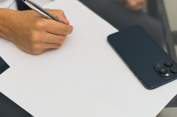 A person is writing on a piece of paper with a pen