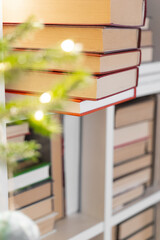Stack of Books with Bokeh Background.Books on a Shelf with Christmas Decor. Close-Up of Books with Christmas Lights Background. 