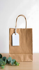 A simple brown paper gift bag with a white tag and green leaves