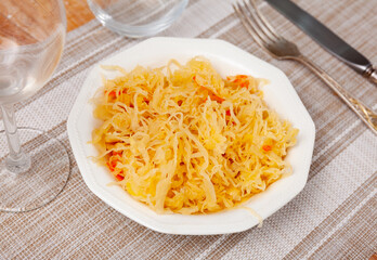 White salad bowl with pickled shredded cabbage with carrot on wooden table. Concept of vegetarian...