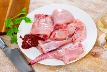 Chopped fresh raw rabbit on plate with greens, garlic and spices prepared for cooking on table. Healthy dietary food