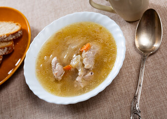 On wooden table there are plate is filled to brim with fresh cabbage soup from selected vegetables...