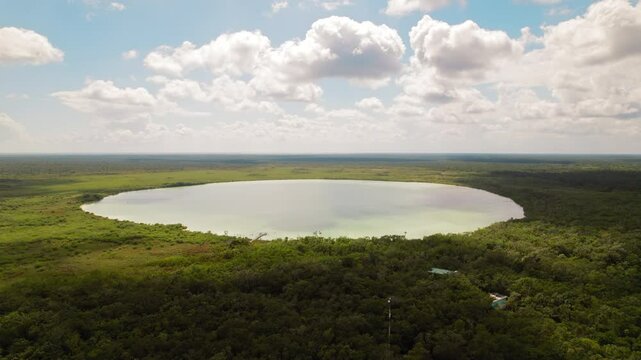 Aerial view of quiet circular lagoon surrounded by dense forest in Yucatan Mexico