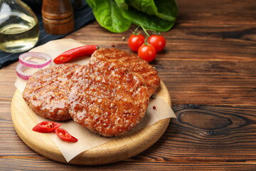 Delicious hamburger patties and spices on wooden table, closeup. Space for text