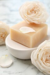 Soap bar and flowers on white marble table, closeup
