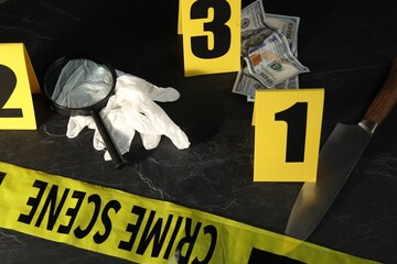 Forensic expert. Yellow crime scene tape, markers and evidences on black table, above view