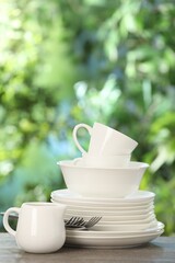 Different clean dishes on wooden table against blurred green background