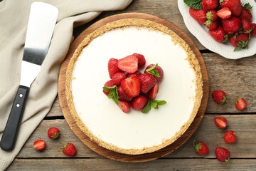 Tasty cheesecake with strawberries, mint and server on wooden table, flat lay