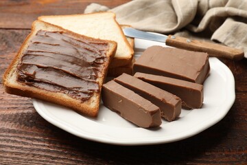 Sandwiches with chocolate butter and knife on wooden table, closeup