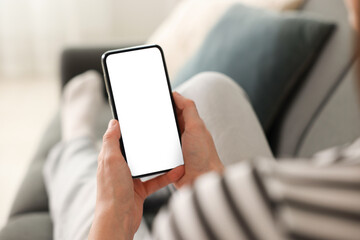 Woman using modern smartphone on sofa at home, closeup