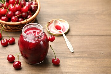 Tasty cherry jam and fresh fruits on wooden table, closeup. Space for text