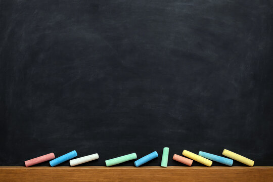Black chalkboard with colorful chalk sticks on wooden ledge blackboard drawing - Powered by Adobe