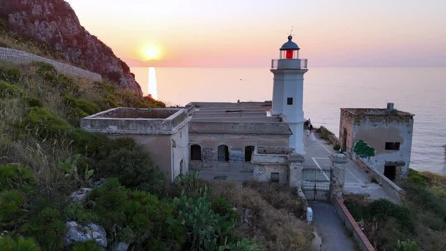 La quiete dopo la tempesta, vista mozzafiato  dall'alto con ripresa da drone  del tramonto che si scaglia sul faro di mongerbino a capo zafferano su scogliera a picco sul mare in sicilia