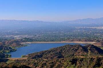 The Hollywood Hills fade into the San Fernando Valley with the San Gabriel Mountains and Santa Susana Mountains in the background and the Encino Reservoir in the foreground