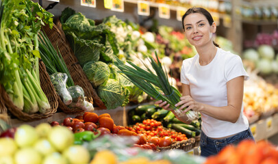 Woman shopping in grocery supermarket - choosing green onion