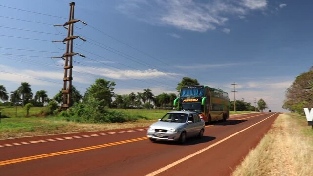 Bus with passengers and car making an improper pass over double yellow lines on Route 12, Wanda, Misiones. Video highlights lack of road safety.