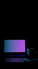 Laptop and mug on a wooden surface in low light.