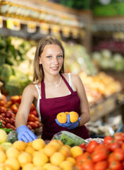 Working in supermarket - female salesman sorts through ripe peaches on the display case