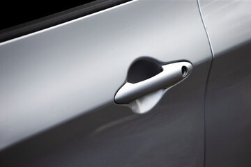 Close-up of a door handle on a silver car.