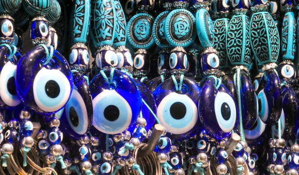 Traditional Turkish Nazar amulets used for protection. Nazar Boncugu Glass ornaments with circular patterns in blue, white, and black, displayed in rows. Close-up of blue evil eye protective amulet