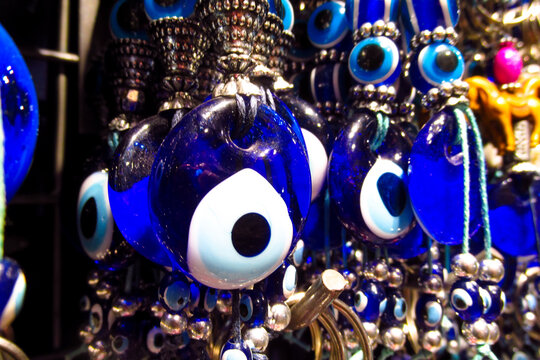 Traditional Turkish Nazar amulets used for protection. Nazar Boncugu Glass ornaments with circular patterns in blue, white, and black, displayed in rows. Close-up of blue evil eye protective amulet