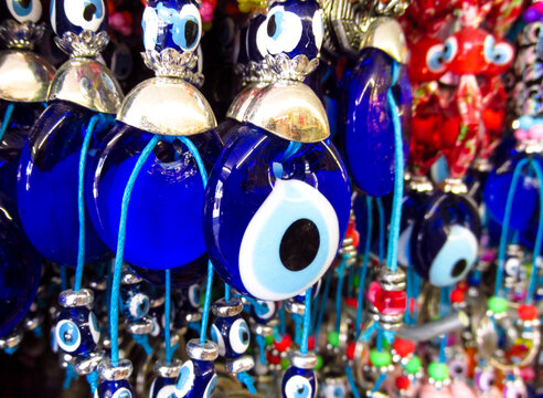 Traditional Turkish Nazar amulets used for protection. Nazar Boncugu Glass ornaments with circular patterns in blue, white, and black, displayed in rows. Close-up of blue evil eye protective amulet