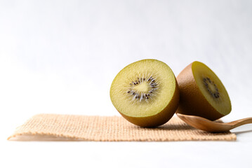 Fresh sungold kiwi fruit on burlap fabric with wooden spoon on white background, Healthy eating