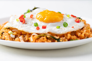 Kimchi fried rice with fried egg, pork, sesame seed, chili, spring onion and seaweed on white plate, Korean food