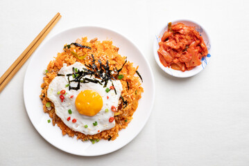 Kimchi fried rice with fried egg, pork, sesame seed, chili, spring onion and seaweed on white plate, Korean food, Top view