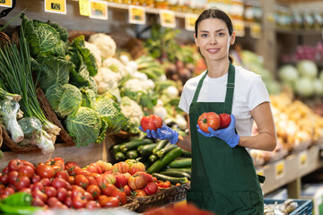 Shop seller put goods on display case. Girl creates stock of tomato in display case, forms...