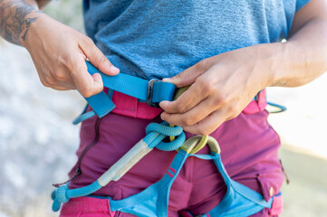 Climber tightening harness getting ready for climbing mountain