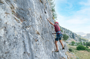 Climber ascending challenging rock face using rope and harness