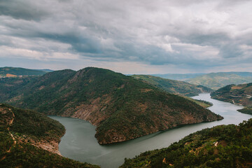 Breathtaking aerial view of Tua River meandering through lush green hills and valleys in Alijo,...