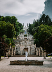 Wide angle view of the Sanctuary of Nossa Senhora dos Remedios in Lamego, Portugal, showcasing the baroque architecture, fountain, and grand stairway ascending to the church under a cloudy sky