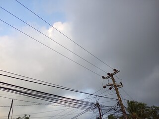 Jumbled Electrical Wires and Utility Pole Against Cloudy Sky