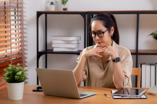 Young asian business woman working with laptop while thinking for planning financial on desk in modern home office, businesswoman planning and thoughtful about working, business and finance.