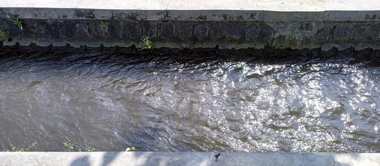 Sunlight Reflecting on Water in Concrete Irrigation Canal