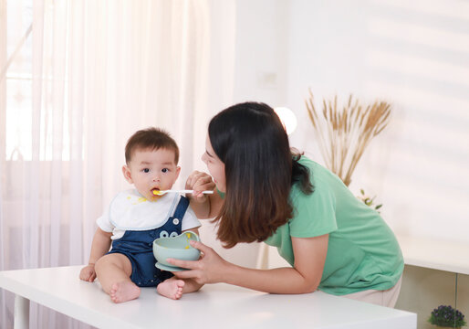 The mother who is feeding her little boy on the table wants to be happy.